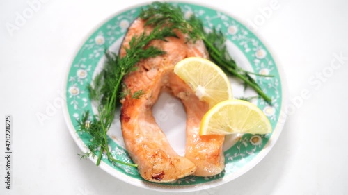 Cooking video. Juicy and appetizing red fish lies on a festive white plate. Green dill, parsley. Smooth camera movement around the dish. Video good for restaurant, cafe menu, fresh food house delivery