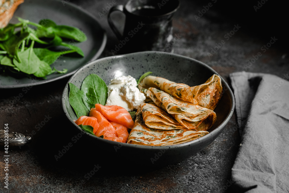 Thin pancakes with herbs, salmon and cream cheese on a plate. crepes Thin pancakes with herbs, salmon and cream cheese on a plate. crepes