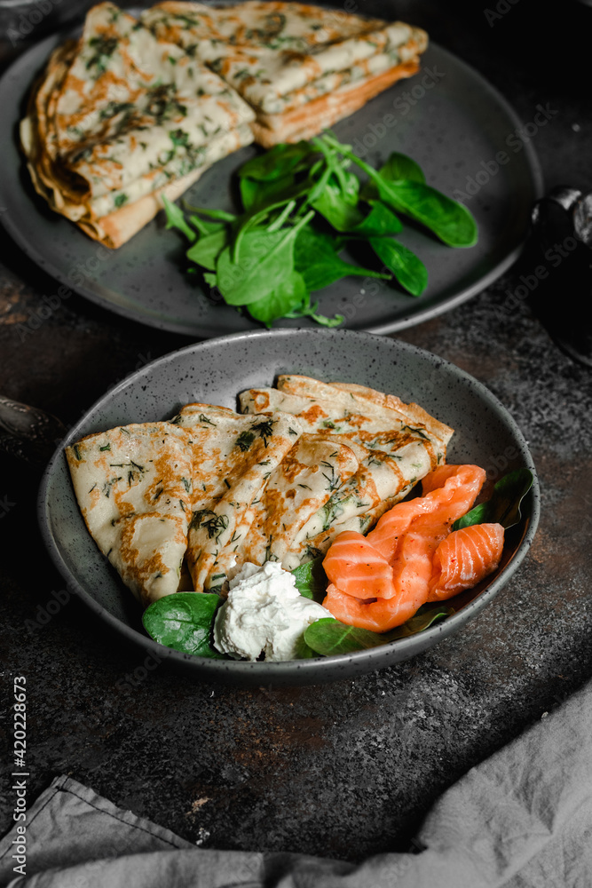 Thin pancakes with herbs, salmon and cream cheese on a plate. crepes Thin pancakes with herbs, salmon and cream cheese on a plate. crepes