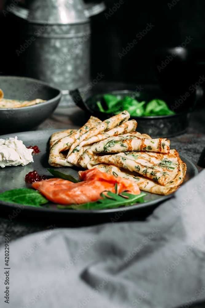 Thin pancakes with herbs, salmon and cream cheese on a plate. crepes Thin pancakes with herbs, salmon and cream cheese on a plate. crepes