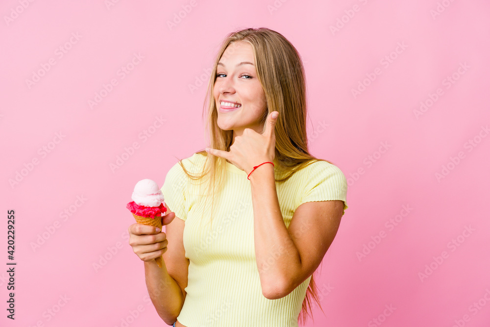 Young russian woman eating an ice cream isolated showing a mobile phone call gesture with fingers. Young russian woman eating an ice cream isolated showing a mobile phone call gesture with fingers.