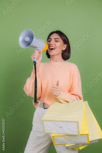 Принти на полотні Young woman in casual peach sweater isolated on green olive color background sho