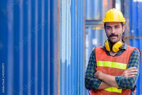 Young confident Caucasian man engineer standing with box container background and check for control loading containers box from Cargo freight ship for import and export, transport