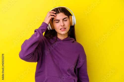 Young caucasian woman listening to music with headphones isolated on pink background tired and very sleepy keeping hand on head. © Asier