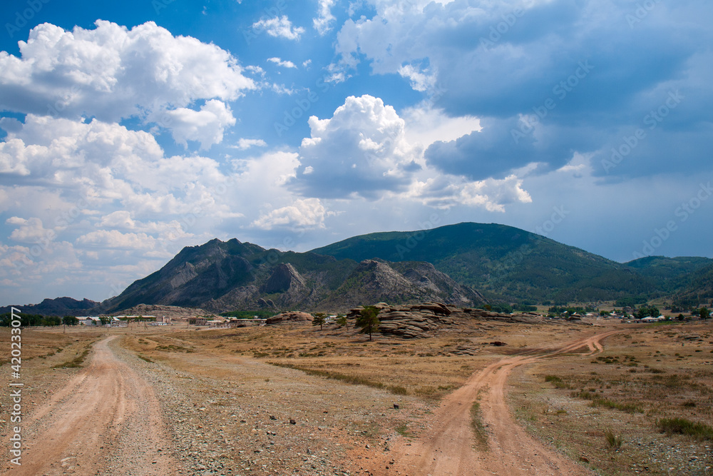 A small village in the valley amongst rocky terrain and some woodland in the Bayanaul National Park, Kazakh Uplands.