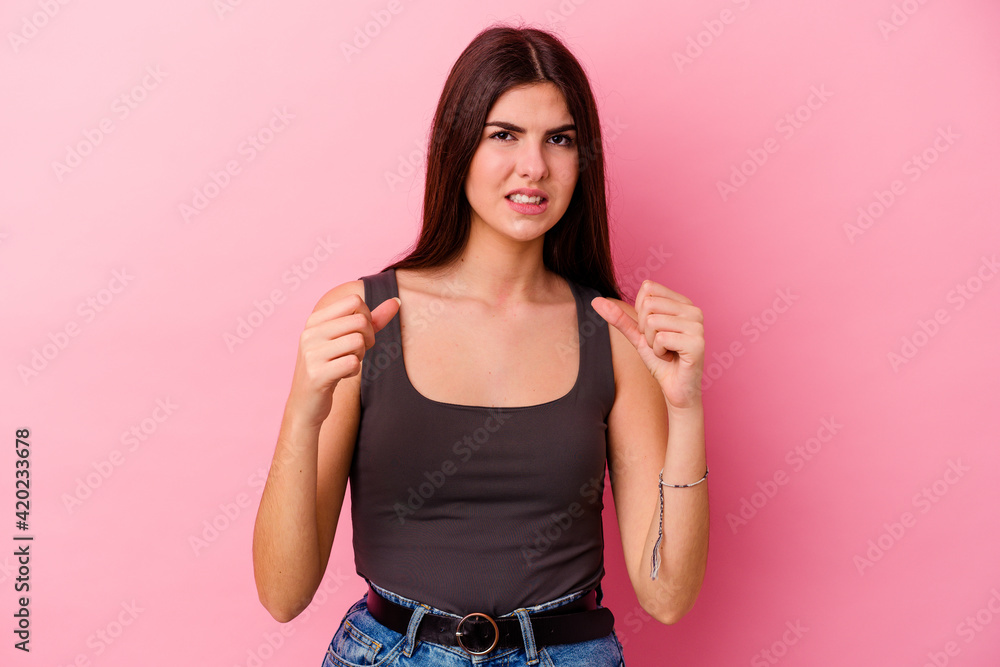 Young caucasian woman isolated on pink background upset screaming with tense hands. Young caucasian woman isolated on pink background upset screaming with tense hands.