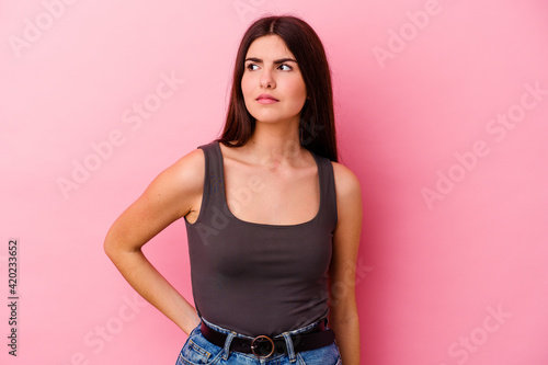 Young caucasian woman isolated on pink background confused  feels doubtful and unsure.