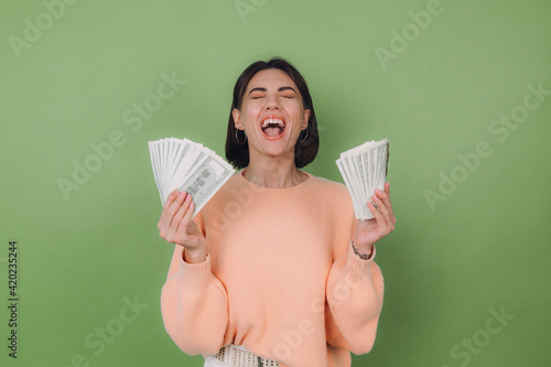 Fotografie Young woman in casual peach sweater  isolated on green olive background  lucky h
