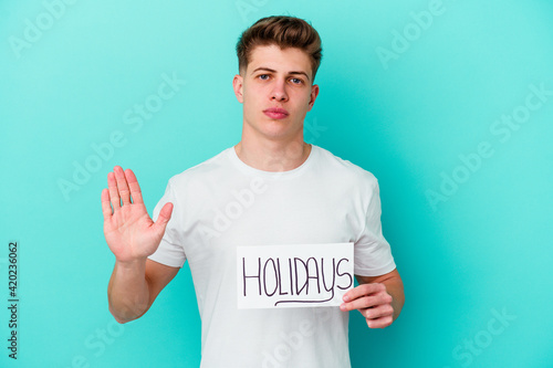 Young caucasian man holding a Holidays placard isolated on blue background © Asier