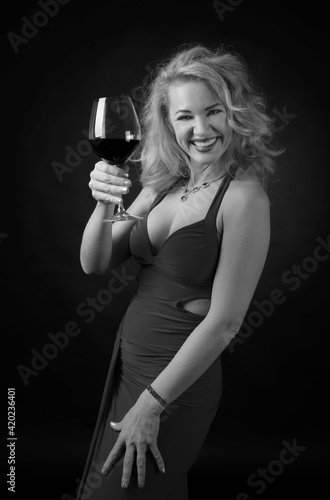 Attractive middle age woman in evening dress with glass of red wine.