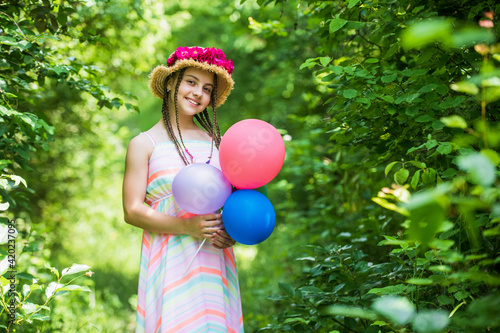 happy teen girl in straw hat with rose flowers in summer nature hold party balloons  childhood