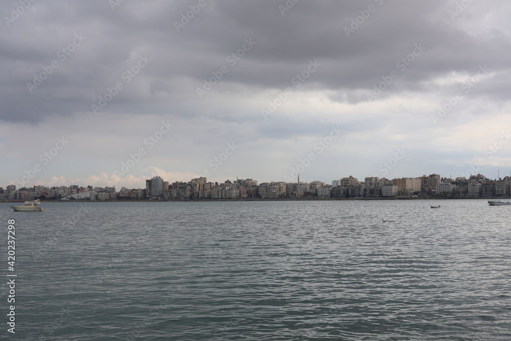 Boats in the harbor. View from coast in Mediterranean Sea. Scenic landscape on a rainy day. Heavy rain clouds. Beautiful Egyptian horizon with a lot of little fishing boats 