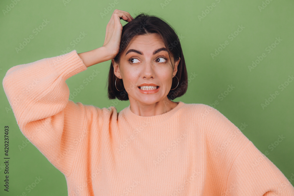 Young stylish woman in casual peach sweater and orange glasses isolated on green olive background preoccupied put hand on head look aside copy space Young stylish woman in casual peach sweater and orange glasses isolated on green olive background preoccupied put hand on head look aside copy space