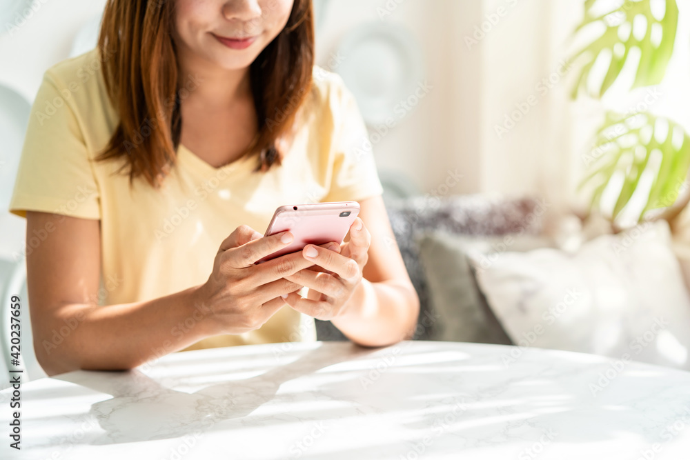 Smile happy young asian woman relaxing and using smart phone in the morning at home Smile happy young asian woman relaxing and using smart phone in the morning at home