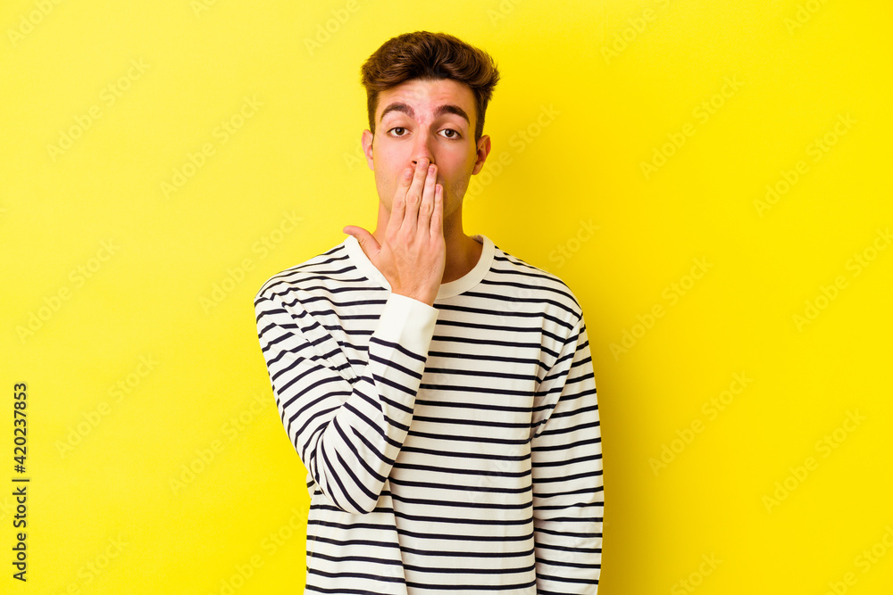 Young caucasian man isolated on yellow background shocked, covering mouth with hands, anxious to discover something new. Young caucasian man isolated on yellow background shocked, covering mouth with hands, anxious to discover something new.