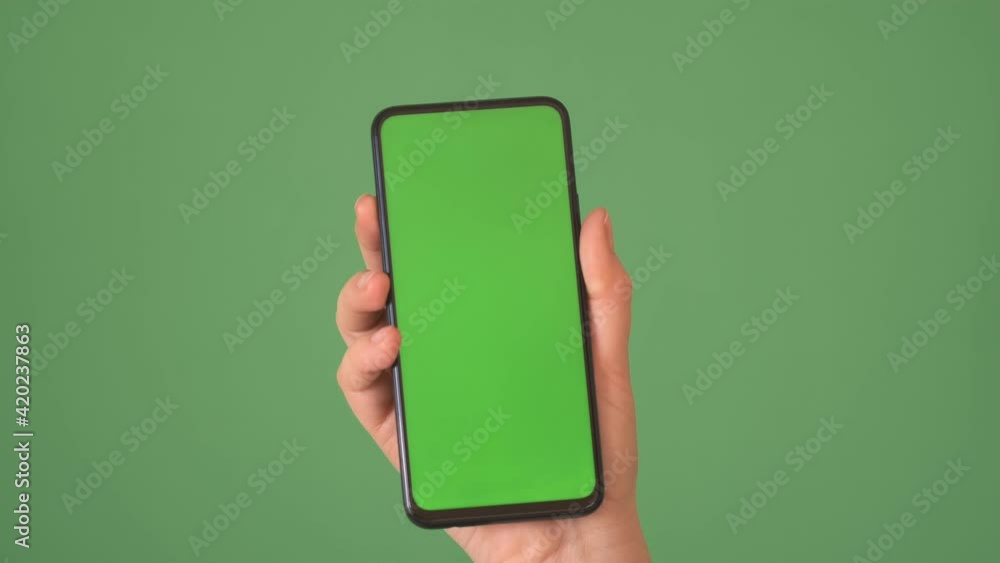 Phone in the hand close up isolated at green background. Phone screen is green chroma key, background chroma key green screen Phone in the hand close up isolated at green background. Phone screen is green chroma key, background chroma key green screen