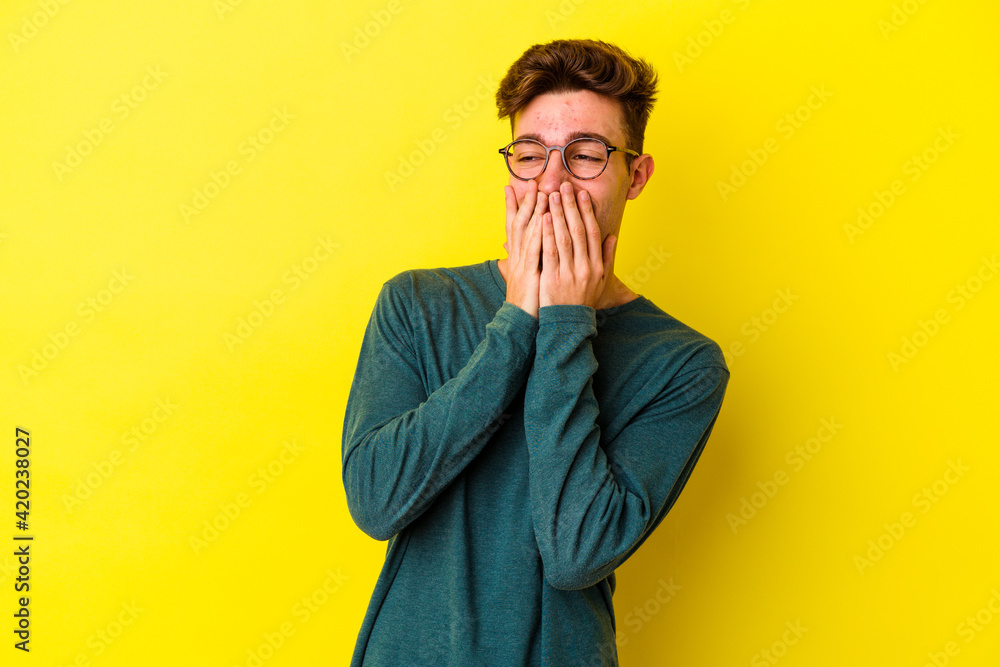 Young caucasian man isolated on yellow background laughing about something, covering mouth with hands. Young caucasian man isolated on yellow background laughing about something, covering mouth with hands.