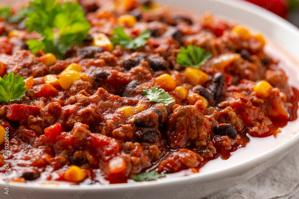 Chilli con Carne with tortilla chips and cheese in white bowl. Mexican food. Chilli con Carne with tortilla chips and cheese in white bowl. Mexican food.