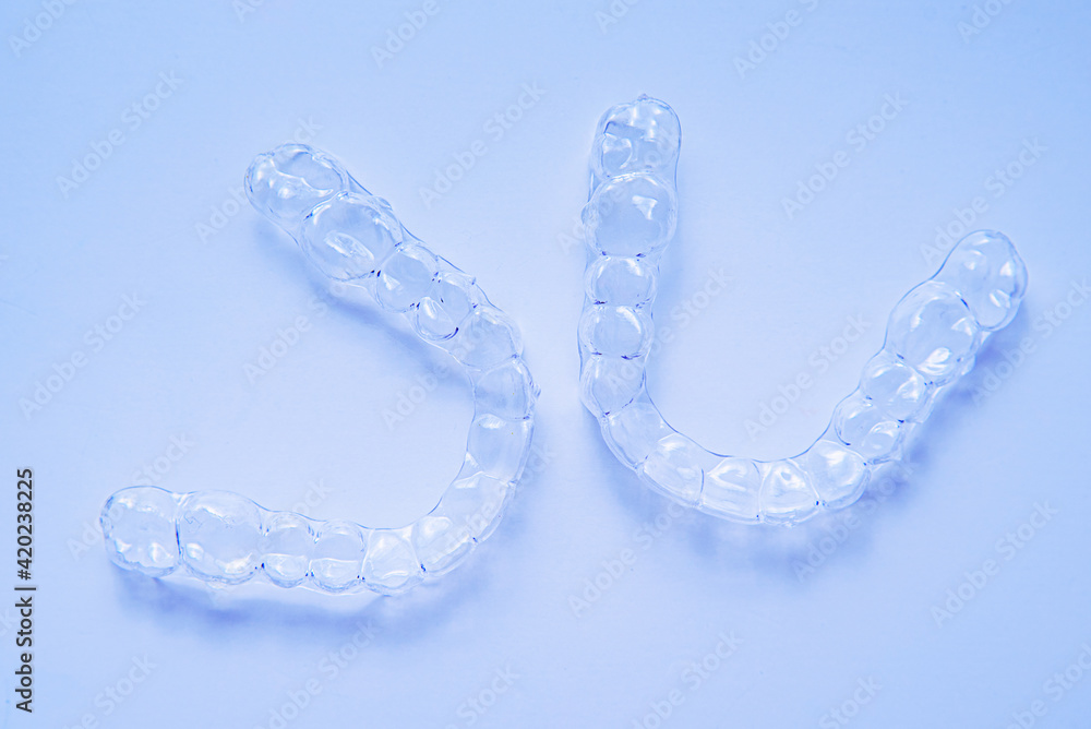 Invisible aligner teeth retainers on a blue background Invisible aligner teeth retainers on a blue background
