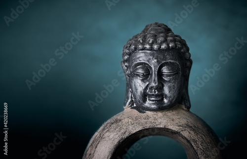 Close-up of a Buddha sculpture on a blue studio background