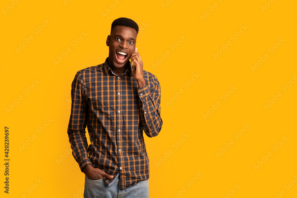 Funny Emotional Black Guy Talking On Cell Phone Over Yellow Background Funny Emotional Black Guy Talking On Cell Phone Over Yellow Background