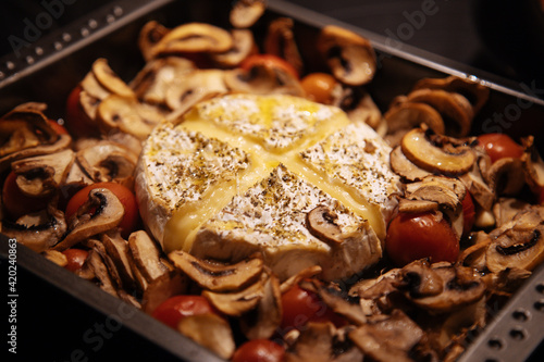 Camembert baked.Cheese with mushrooms and tomatoes in a baking sheet.Baked Camembert cheese with vegetables