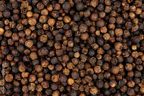 Whole dried black peppercorn spice seasoning background