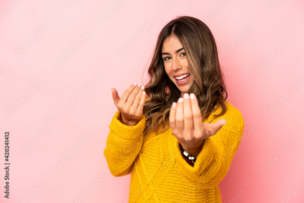 Young caucasian woman isolated pointing with finger at you as if inviting come closer. Young caucasian woman isolated pointing with finger at you as if inviting come closer.
