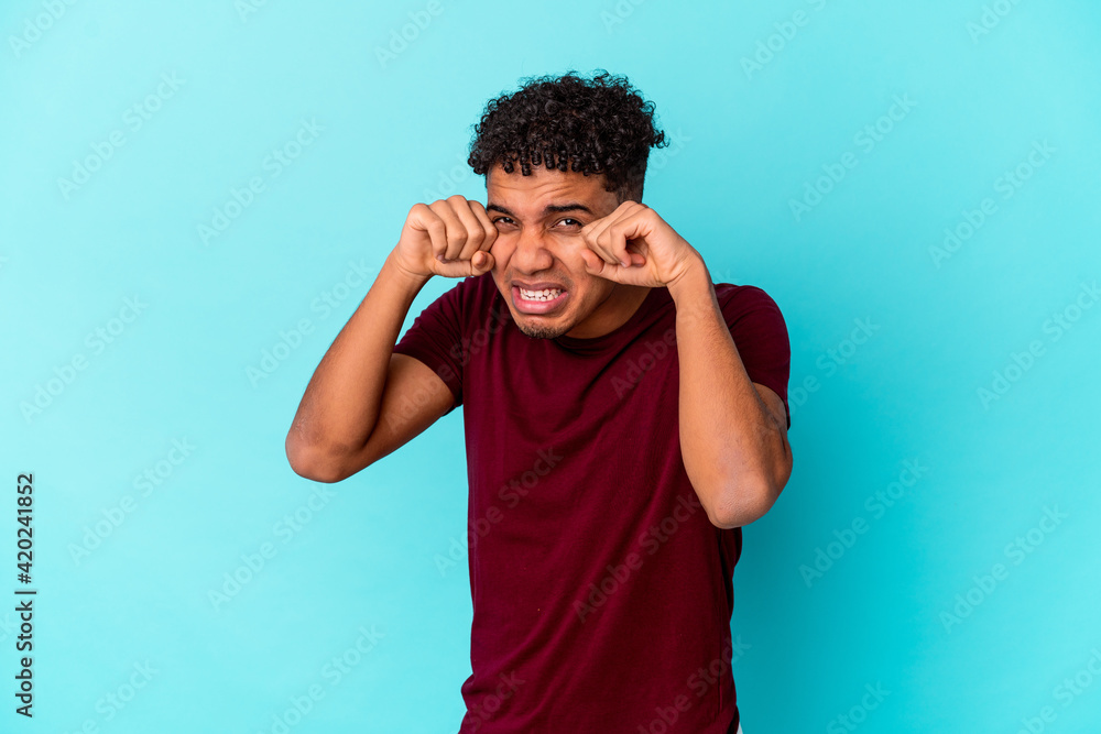 Young african american curly man isolated on blue whining and crying disconsolately. Young african american curly man isolated on blue whining and crying disconsolately.