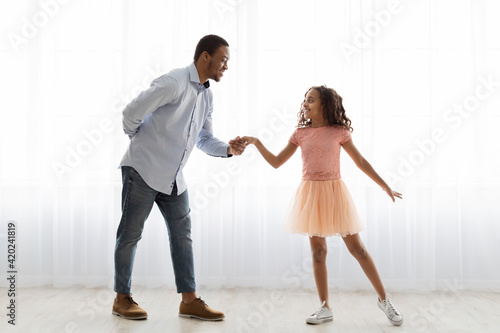 Black father and daughter dancing at home