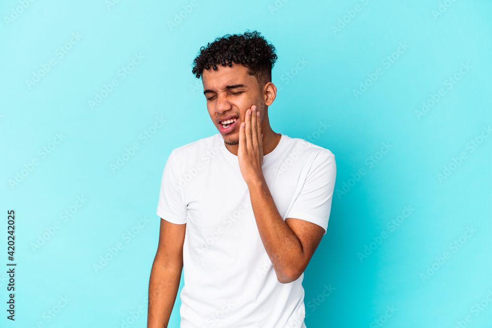Young african american curly man isolated on blue having a strong teeth pain, molar ache. Young african american curly man isolated on blue having a strong teeth pain, molar ache.
