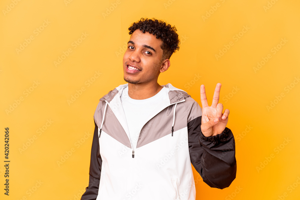 Young african american curly man isolated on purple showing victory sign and smiling broadly. Young african american curly man isolated on purple showing victory sign and smiling broadly.