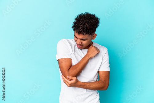 Young african american curly man isolated on blue massaging elbow, suffering after a bad movement.