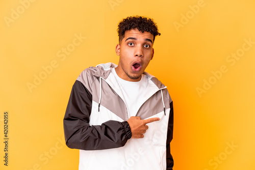 Young african american curly man isolated on purple pointing to the side © Asier