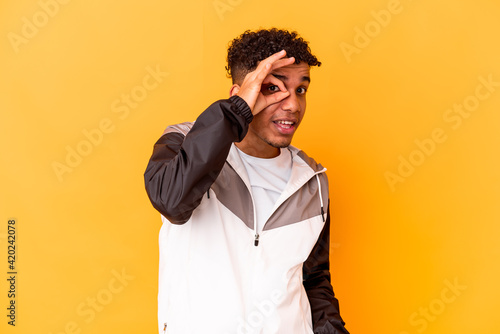 Young african american curly man isolated on purple excited keeping ok gesture on eye.