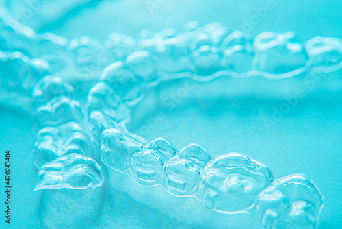 Invisible dental teeth brackets tooth aligners on turquoise background. Plastic braces dentistry retainers to straighten teeth.
