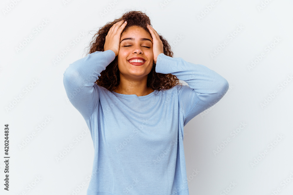 Young african american woman isolated on white background laughs joyfully keeping hands on head. Happiness concept. Young african american woman isolated on white background laughs joyfully keeping hands on head. Happiness concept.