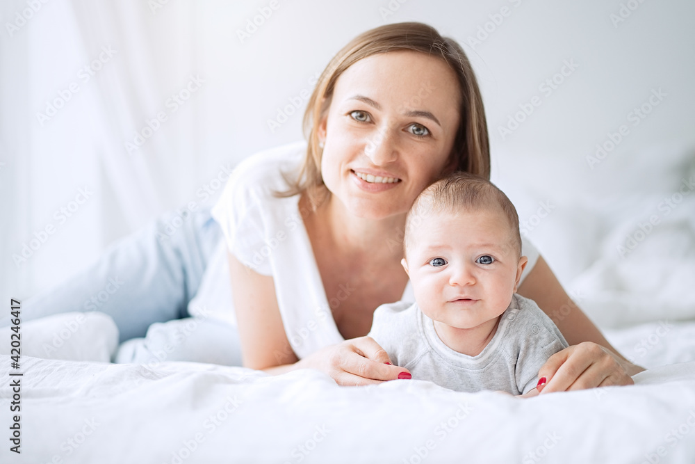 Portrait of a beautiful mother smiling with her 3 month old baby in bedroom Portrait of a beautiful mother smiling with her 3 month old baby in bedroom