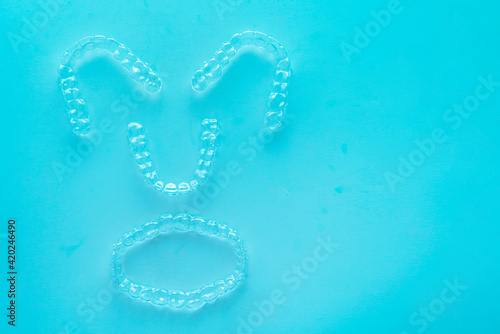 Invisible dental teeth brackets tooth aligners on turquoise background. Plastic braces dentistry retainers to straighten teeth.
