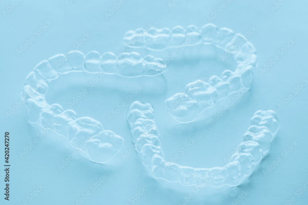 Invisible aligner teeth retainers on a blue background Invisible aligner teeth retainers on a blue background