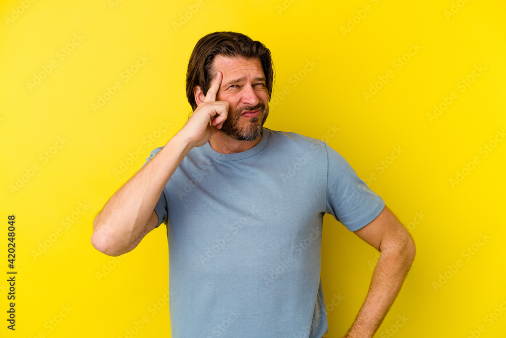 Middle age caucasian man isolated on yellow background pointing temple with finger, thinking, focused on a task. Middle age caucasian man isolated on yellow background pointing temple with finger, thinking, focused on a task.