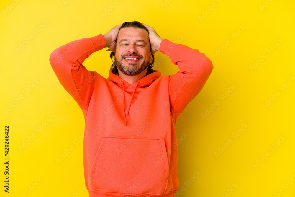 Middle age caucasian man isolated on yellow background laughs joyfully keeping hands on head. Happiness concept. Middle age caucasian man isolated on yellow background laughs joyfully keeping hands on head. Happiness concept.