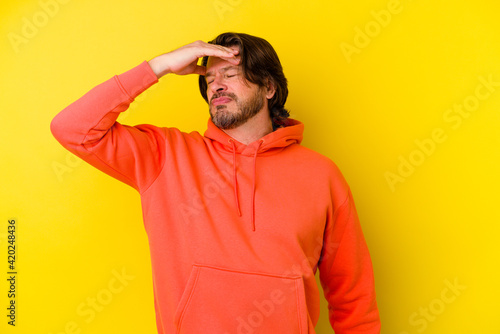 Middle age caucasian man isolated on yellow background touching temples and having headache.