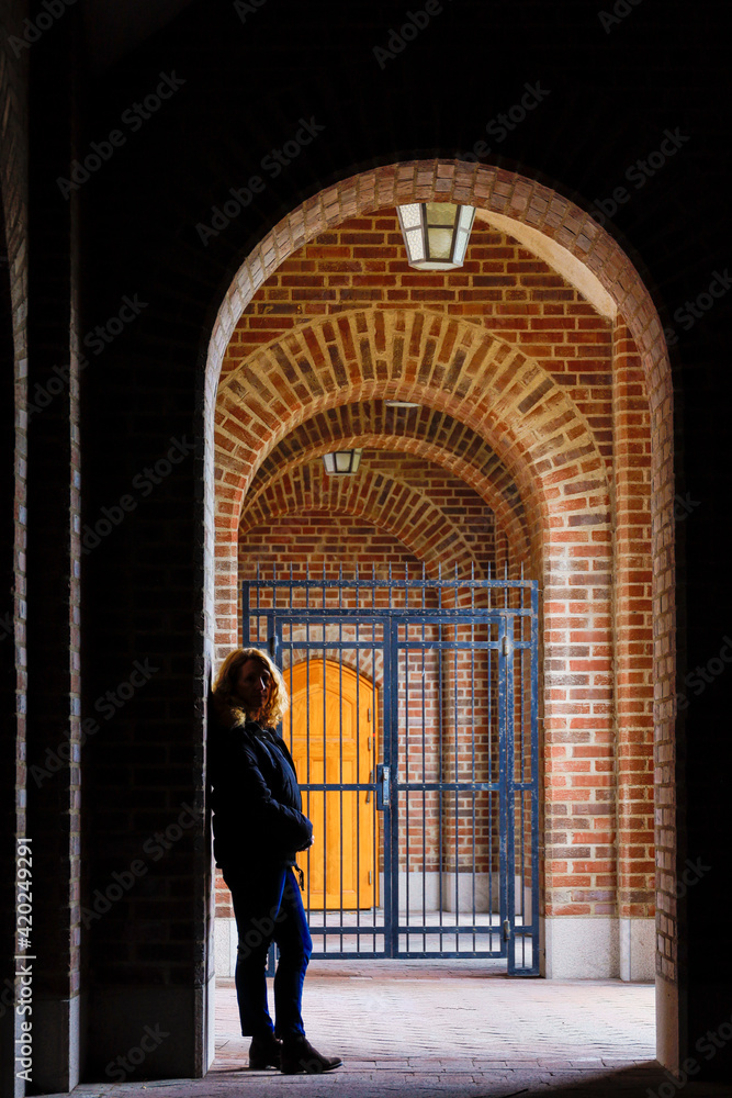Stockholm, Sweden A woman leans against an archway in an outdoor corridor at the Stockholm Stadion Olympic stadium.