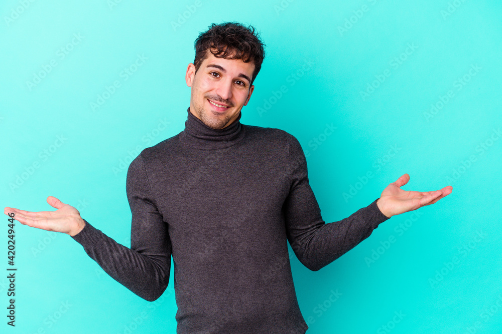 Young caucasian man isolated on blue background showing a welcome expression. Young caucasian man isolated on blue background showing a welcome expression.
