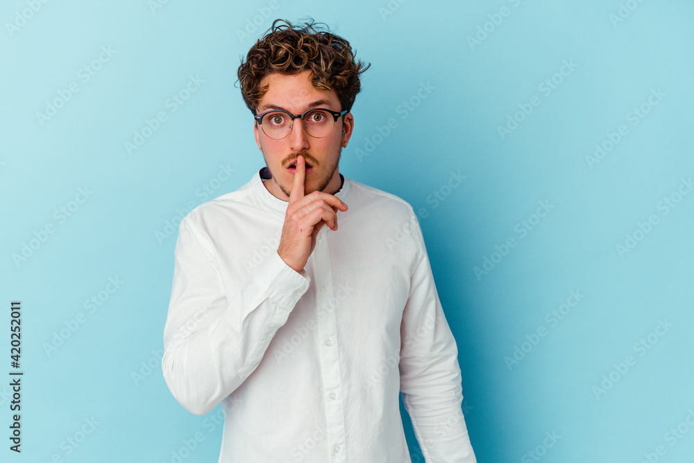 Young caucasian business man isolated on blue background keeping a secret or asking for silence. Young caucasian business man isolated on blue background keeping a secret or asking for silence.