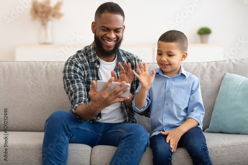 Black Father And Son Making Video Call Using Smartphone Indoor