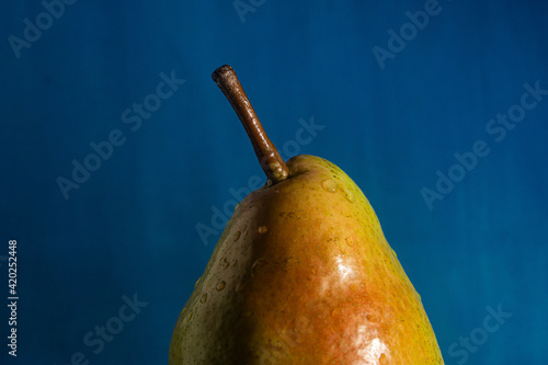 Obraz na płótnie ripe pear with water drops in front of blue, as a close-up w salonie