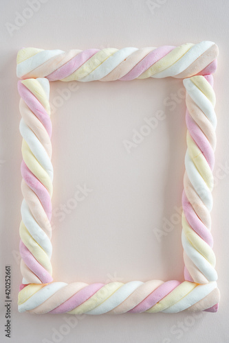 Top down view of marshmallow sweets (in Dutch: kabelspekjes) in the form of a picture frame on soft pink background photo