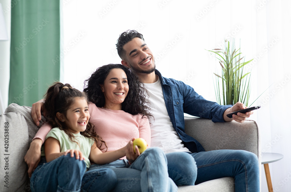 Happy arabic family of three relaxing and watching tv at home Happy arabic family of three relaxing and watching tv at home